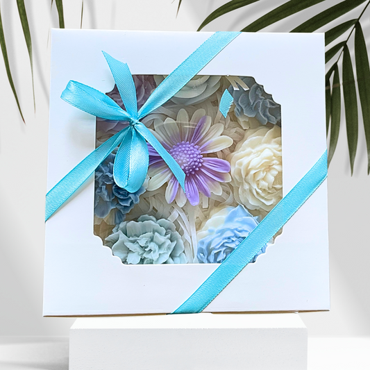 Gift box with a blue ribbon containing colorful flower-shaped objects on a white background.PASTEL FLOWERS WAX MELTS GIFT BOX