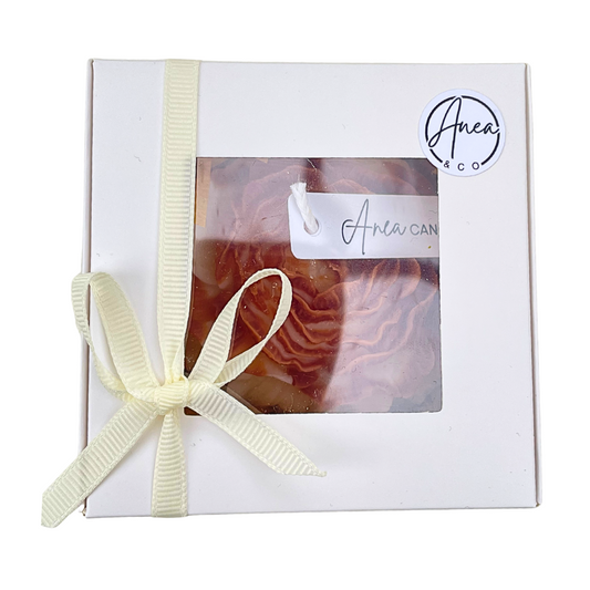 Gift box with a candle inside, tied with a ribbon, featuring the brand 'Anea & Co'. PEONY CINNAMON BUN CANDLE GIFT BOX