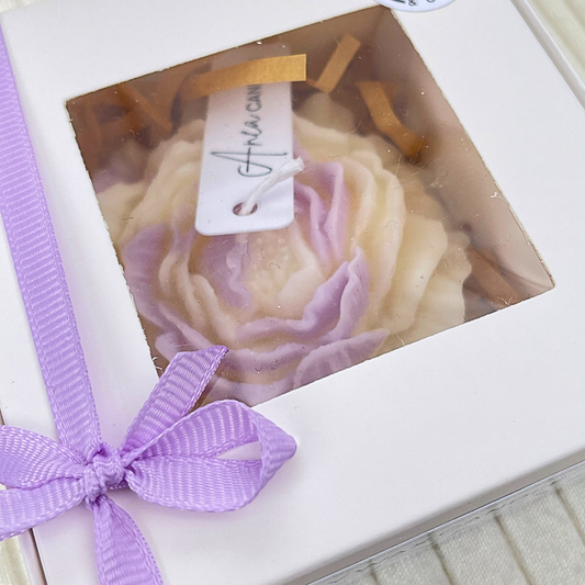 Gift box with a purple ribbon and a product inside, featuring a visible brand name. PEONY FRESH LINEN CANDLE GIFT BOX 