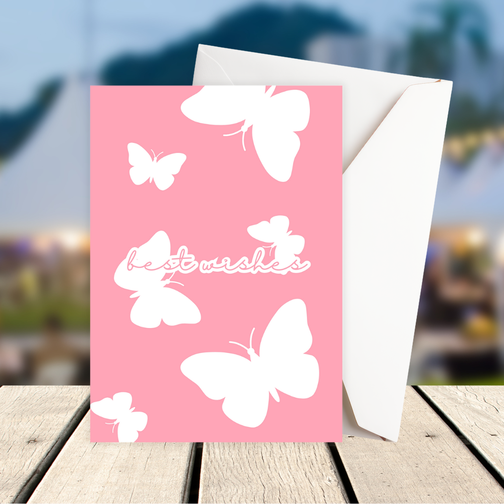 Pink Butterflies Best Wishes Greeting Card with white butterflies and 'best wishes' text on a wooden surface with blurred background