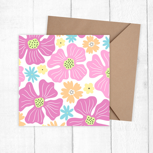 Floral patterned card with a brown envelope on a white wooden surface. Pink Flowers Birthday Card