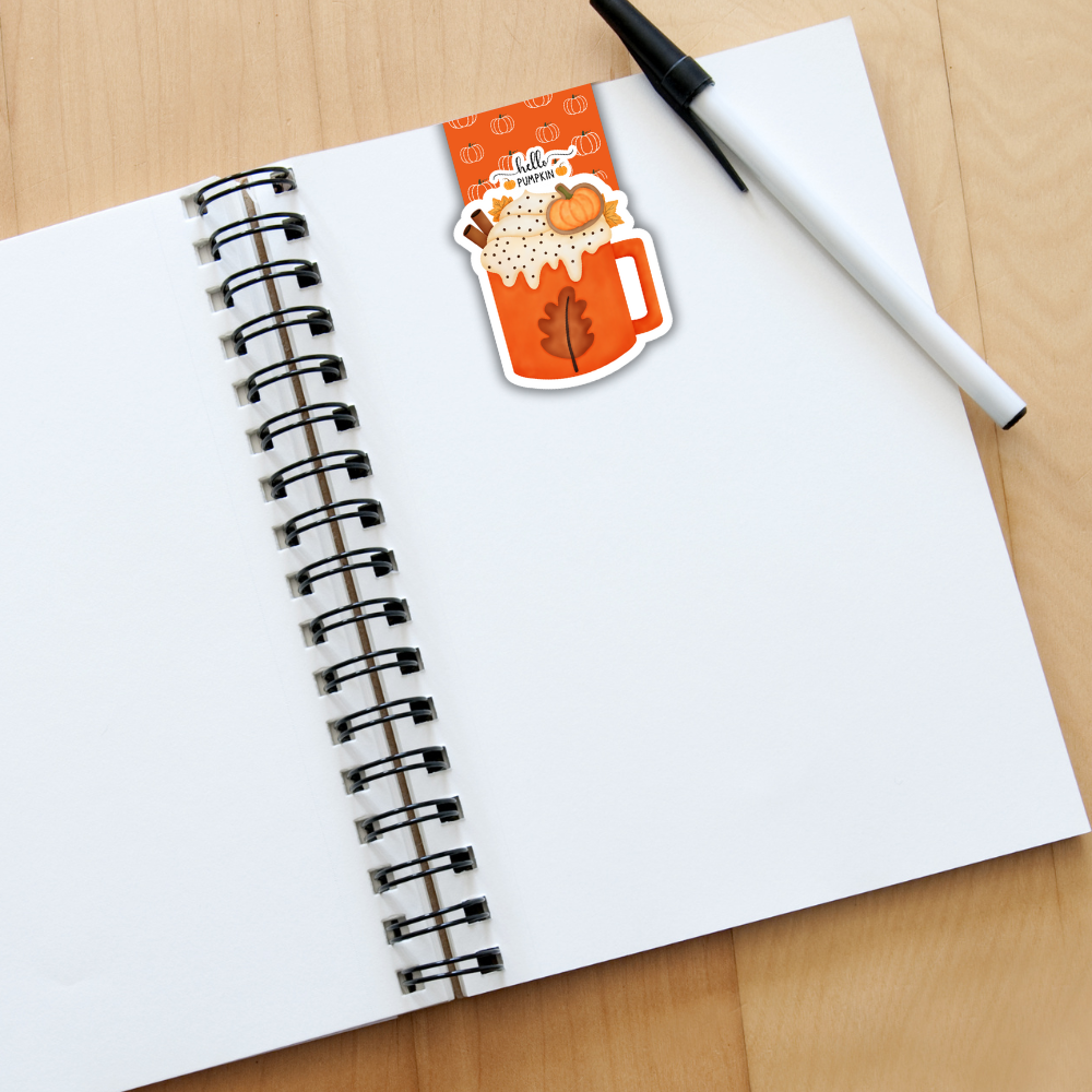 Open notebook with a pen and a decorative sticker on a wooden surface. Pumpkin Latte Magnetic Bookmark