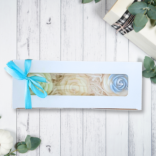 Marble-patterned box with a blue ribbon on a wooden surface with greenery. ROSES SNOW PIXIE CANDLE