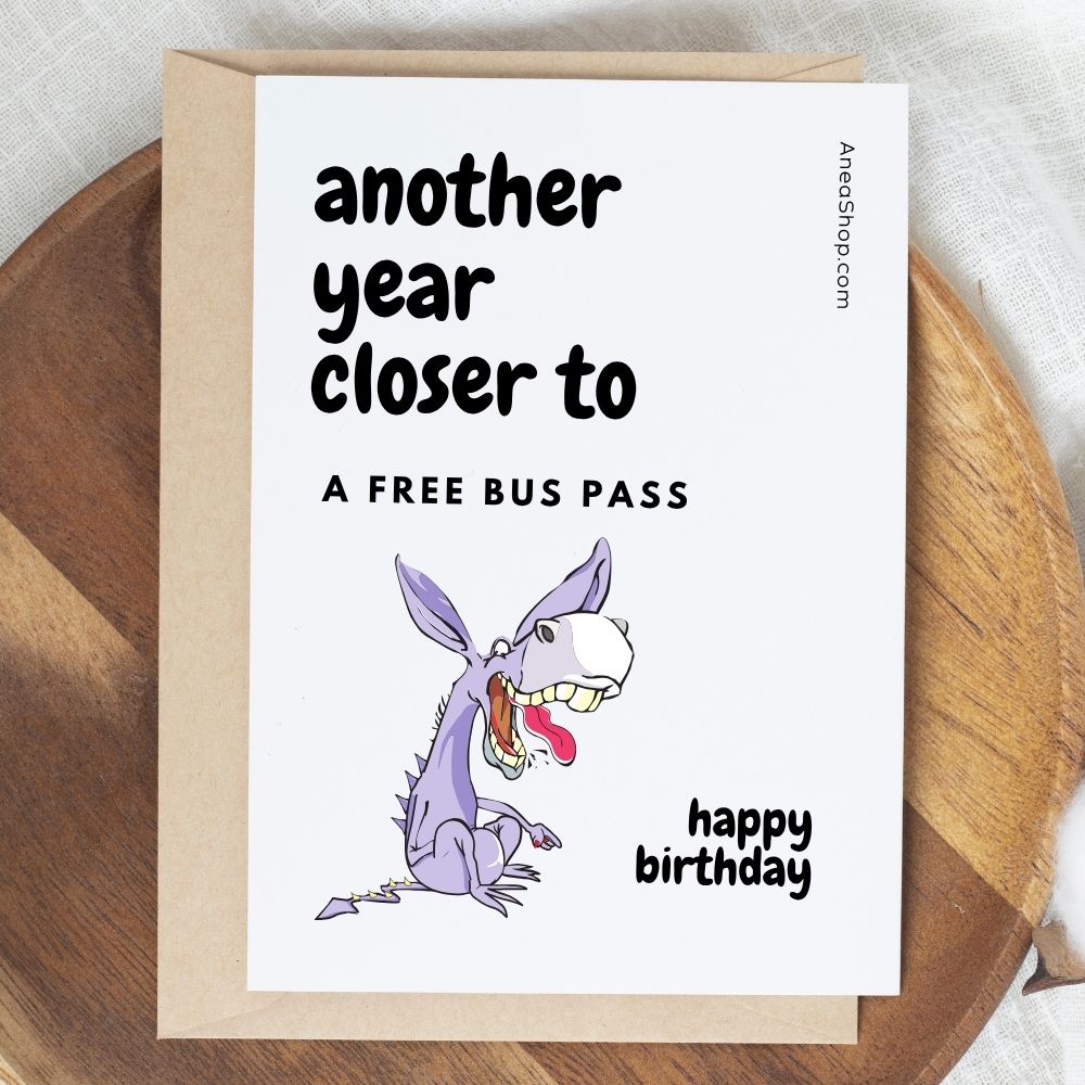 Birthday card with cartoon dragon and humorous text on a wooden surface. Rude Birthday Card