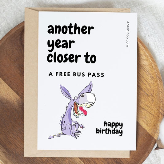 Birthday card with cartoon dragon and humorous text on a wooden surface. Rude Birthday Card