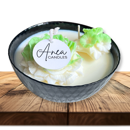 Candle in a decorative bowl with 'Anea Candles' label on a wooden surface. SPRING PEONY SOY CANDLE