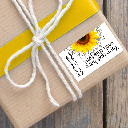 Gift wrapped in brown paper with a yellow ribbon and sunflower-themed label on a wooden surface.SUNFLOWER PERSONALISED GIFT TAG