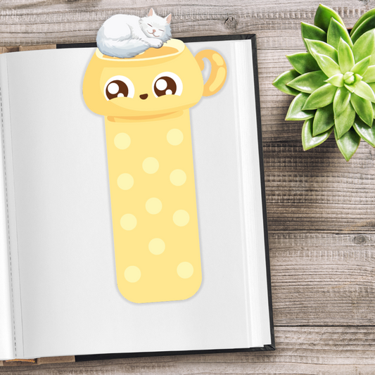 Yellow polka dot bookmark with a cat design on an open book, next to a succulent plant. Sleeping Cat Bookmark