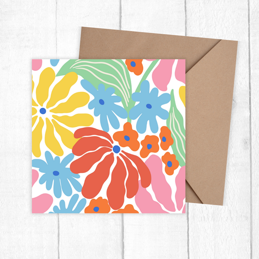 Colourful floral card with a brown envelope on a white wooden surface. Summer Flowers Birthday Card
