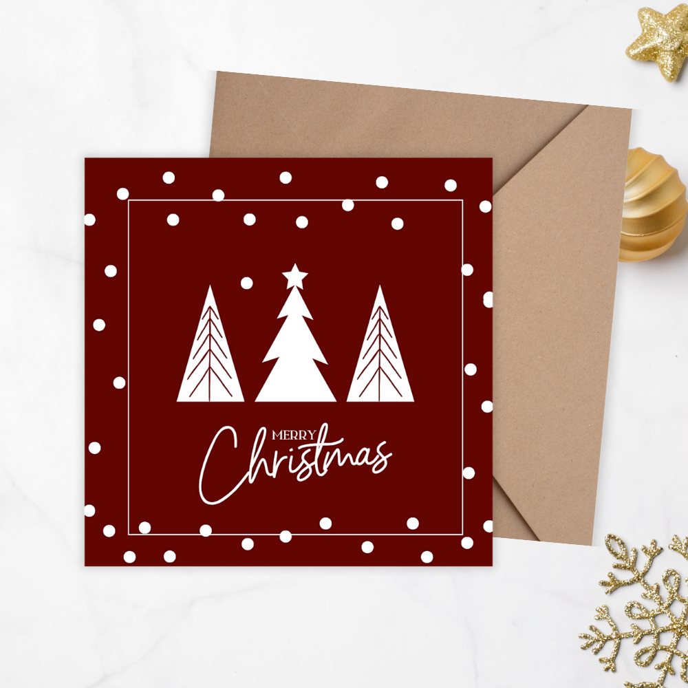Red Christmas card with white trees and 'Merry Christmas' text, accompanied by a brown envelope on a light gray background. Trees Burgundy Christmas Card