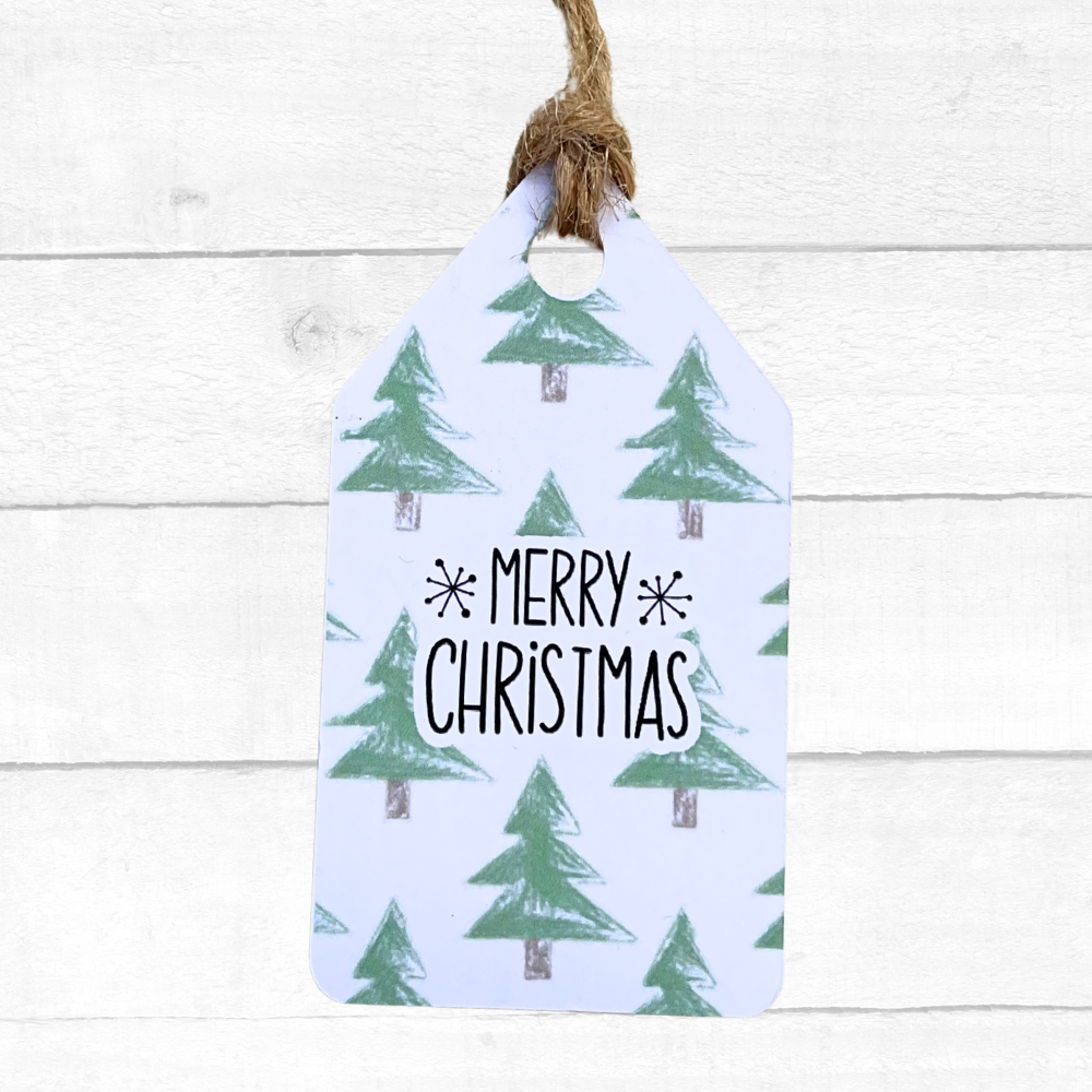 Gift tag with Christmas tree pattern and 'Merry Christmas' text on a white wooden background. Trees Christmas Gift Tag Set