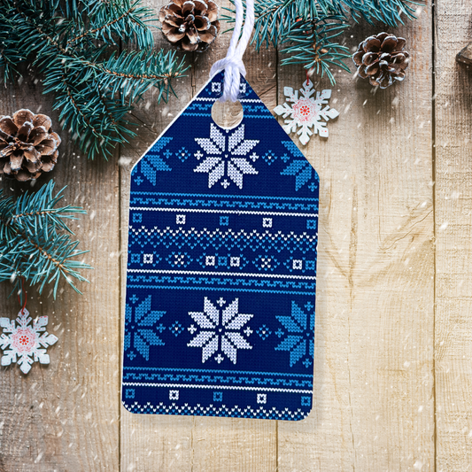 Blue and white patterned Christmas tag with snowflakes on a wooden background with pine branches and cones.Ugly Sweater Christmas Gift Tag Set