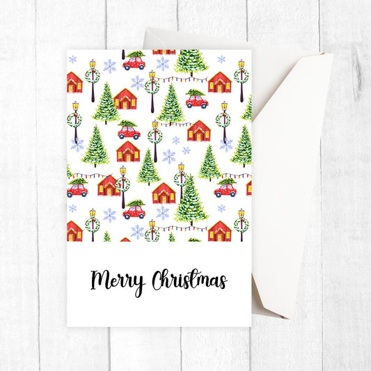 Christmas-themed card with houses, trees, and cars on a white background. VILLAGE MERRY CHRISTMAS CARD