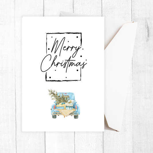 Framed artwork with 'Merry Christmas' text and a blue truck carrying a Christmas tree on a white background.Vintage Car Christmas Card