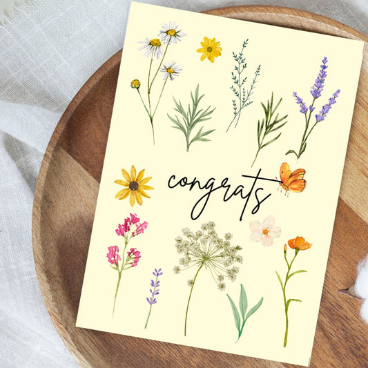 Greeting card with floral designs and 'congrats' text on a wooden surface. Wild Flowers Congratulations Card