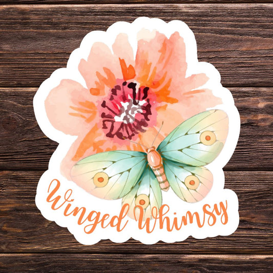 Floral and butterfly design with 'Winged Whimsy' text on a wooden background. Winged Whimsy Butterfly Sticker