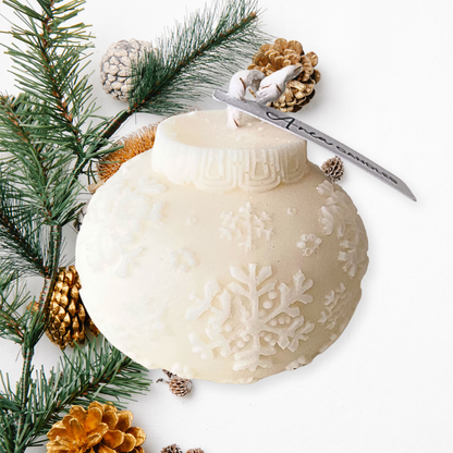 Decorative white ornament with snowflake pattern on a white background with pine branches and pinecones. BAUBLE CHRISTMAS CANDLE