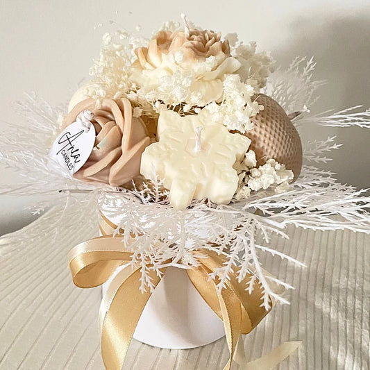 Decorative flower arrangement with white and beige flowers, gold ribbon, and a white tag on a textured surface. christmas candle ornaments