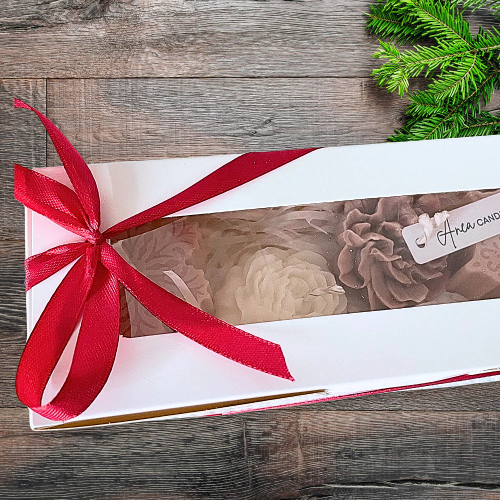 Gift box with a red ribbon on a wooden surface with greenery. CHRISTMAS SPICE CANDLE GIFT BOX