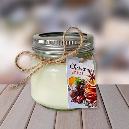 Jar candle labeled 'Christmas Spice' on a wooden surface with a blurred background. CHRISTMAS SPICE NATURAL SOY CANDLE