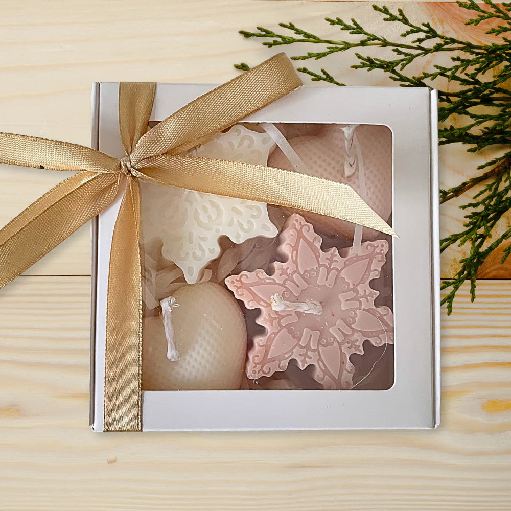 Decorative candles in a box with a gold ribbon on a wooden surface. CHRISTMAS ORNAMENTS CANDLE GIFT BOX