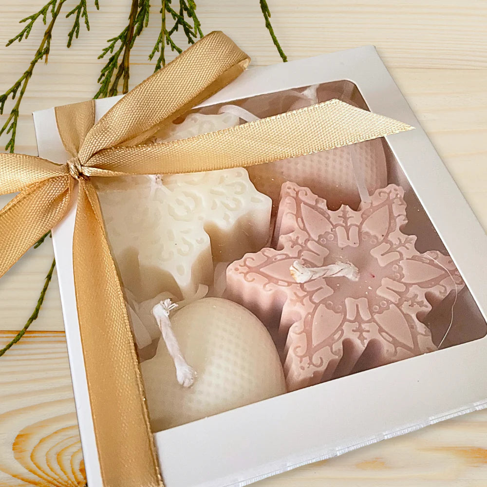 Decorative candles in a box with a gold ribbon on a wooden surface. CHRISTMAS ORNAMENTS CANDLE GIFT BOX
