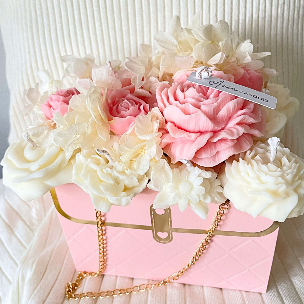 Decorative flower arrangement in a pink box with a gold chain on a textured white background. PINK CANDLE FLOWER BOUQUET BAG