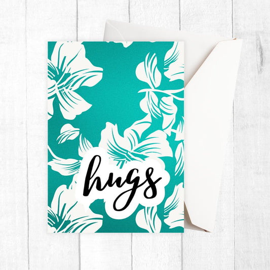 Card with white floral design and 'hugs' text on a teal background. hugs floral happy birthday card