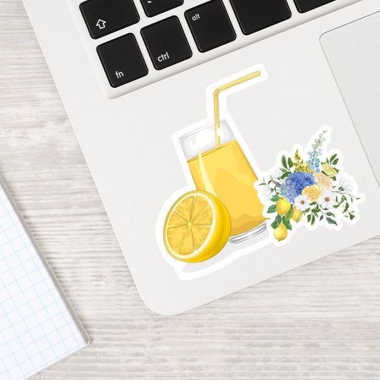 Sticker of a glass of lemonade with a straw and lemon slice, placed on a laptop keyboard.lemon juice and flowers sticker