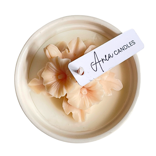 Decorative candle with floral designs and 'Area Candles' label on a white background. natural flower SOY CANDLE