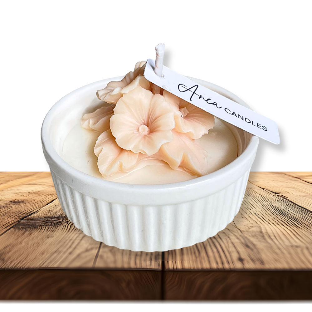 Candle in a white ramekin with a floral design on a wooden surface, branded 'Aria Candles'. natural flower SOY CANDLE