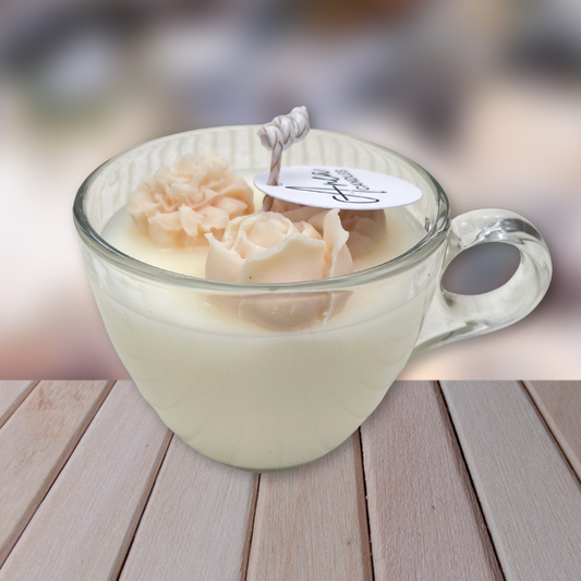 Glass mug with a flower-shaped candle on a wooden surface. SANDALWOOD CINNAMON BUN CANDLE