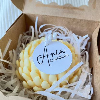 Yellow candle in a box with 'Anea Candles' label. SANDALWOOD YELLOW FLOWER CANDLE