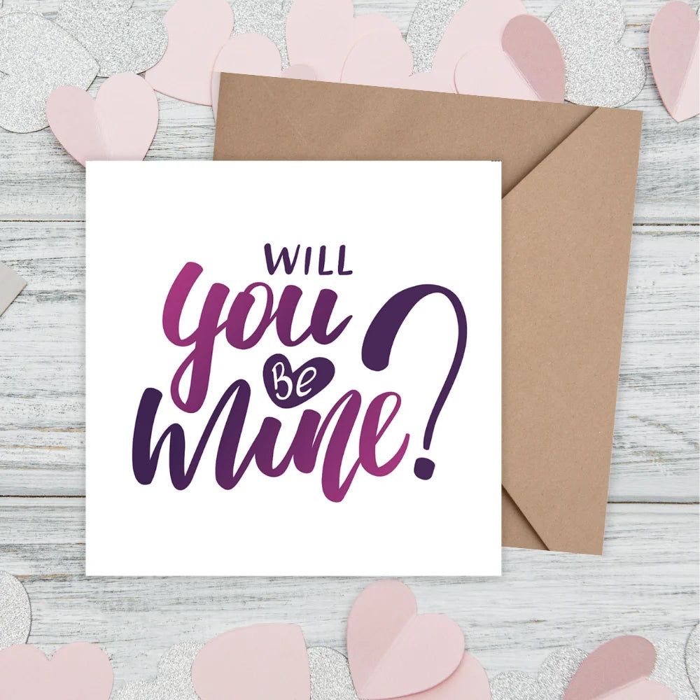 Card with 'Will you be mine?' text on a wooden surface with pink heart decorations. valentine's cards